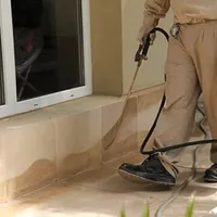 General pest control technician spraying exterior perimeter around a home in Naperville, IL