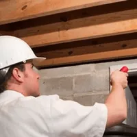 Termite inspection technician checking a basement wall and framing for termite activity in Naperville, IL